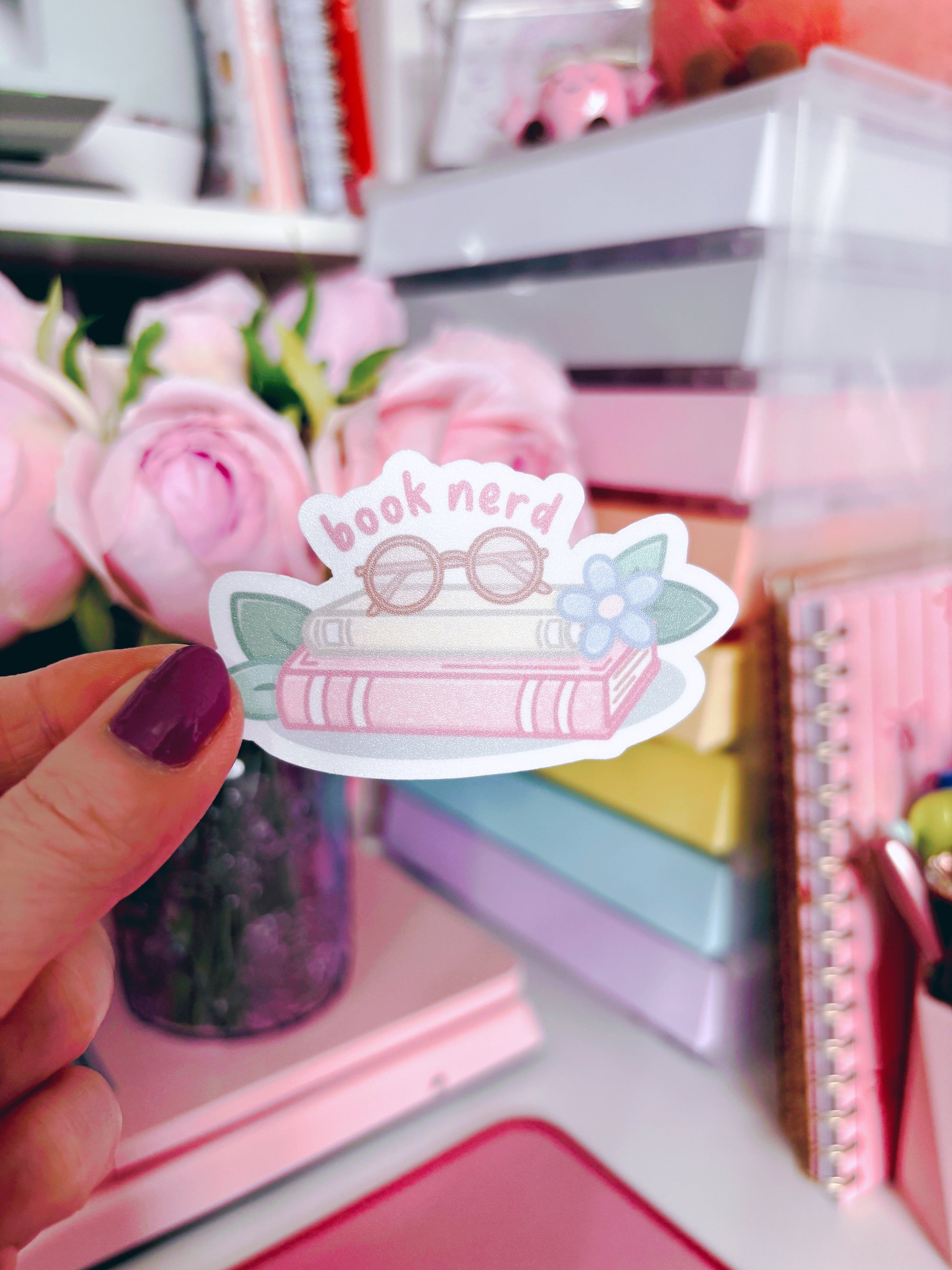 Sticker with 'book nerd' design held in front of a colorful stationery background