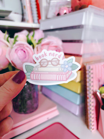Sticker with 'book nerd' design held in front of a colorful stationery background