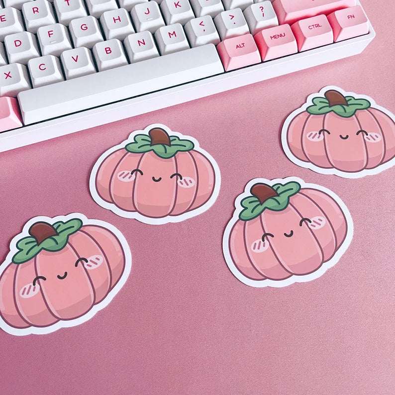 Pink pumpkin stickers on a pink surface with a keyboard in the background