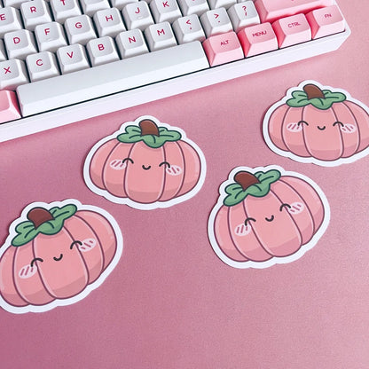 Pink pumpkin stickers on a pink surface with a keyboard in the background