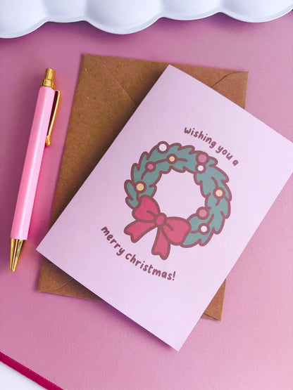 Christmas card with wreath design and pen on pink background